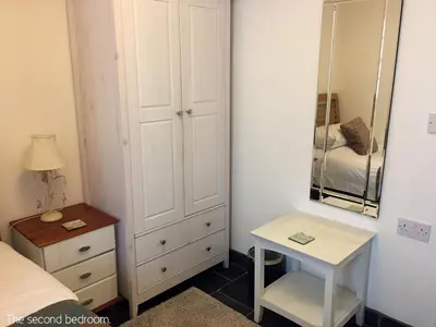 a bedroom with a bed and a dresser and a mirror at Museum Apartment in Looe