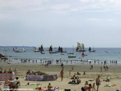 a group of people on a beach with boats in the water at Museum Apartment in Looe