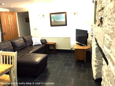 a living room with a black leather couch and a tv at Museum Apartment in Looe
