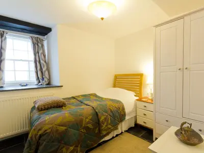 a bedroom with a bed and a dresser and a window at Museum Apartment in Looe