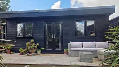 a black tiny house sitting on a wooden deck at The Little Cabin in St Ives