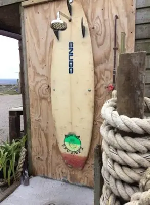 a surfboard attached to a wooden wall with a rope at The Little Cabin in St Ives