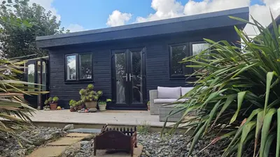 a black tiny house on a wooden deck at The Little Cabin in St Ives