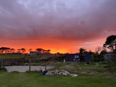 a sunset in a field with a cloudy sky at The Little Cabin in St Ives