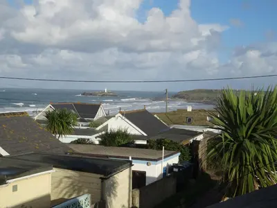 a view of the ocean with a lighthouse in the distance at Gwithian, Sea Dream Beach Chalet in Gwithian