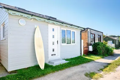 a surfboard leaning against the side of a house at Gwithian, Sea Dream Beach Chalet in Gwithian