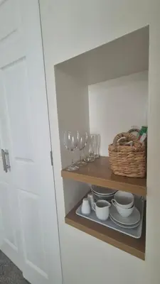 a cupboard with wine glasses and plates and a basket at Tregarthen - Adult Only in Newquay