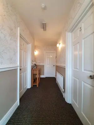 an empty hallway with a white door and a table at Tregarthen - Adult Only in Newquay
