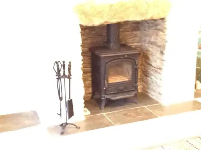 a fireplace with a stove in a room at Re-imagined Stone Barns in the Country Near the Coast in Padstow