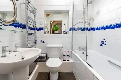 a white bathroom with a toilet and a sink at Re-imagined Stone Barns in the Country Near the Coast in Padstow
