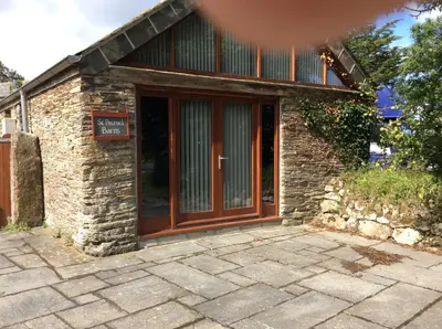 a brick building with a door with a sign on it at Re-imagined Stone Barns in the Country Near the Coast in Padstow
