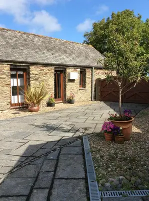 a stone house with a tree in front of it at Re-imagined Stone Barns in the Country Near the Coast in Padstow