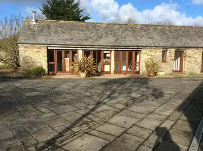 a stone house with a driveway in front of it at Re-imagined Stone Barns in the Country Near the Coast in Padstow