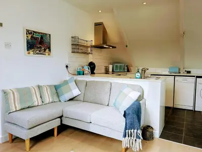 a living room with a couch and a kitchen at Fowey River Views in Fowey