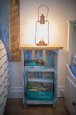 a table with books and a light on top at Driftwood in Bude