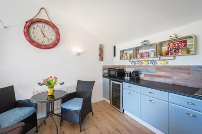 a kitchen with a table and a clock on the wall at Driftwood in Bude