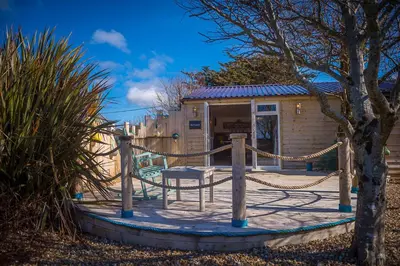 a small shack with a hammock and a playground at Driftwood in Bude