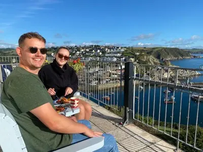 two people sitting on a bench overlooking a harbor at Honeycombe House in Mevagissey