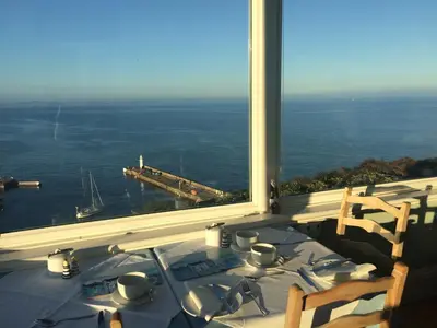 a table with a view of the ocean from a window at Honeycombe House in Mevagissey