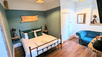 a bedroom with a bed and a blue couch at Wheal Tor Hotel & Glamping in Liskeard