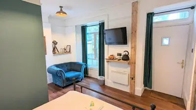 a living room with a blue chair and a television at Wheal Tor Hotel & Glamping in Liskeard