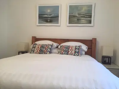 a bedroom with a white bed with two pictures on the wall at SeaQuest 5 in Newquay