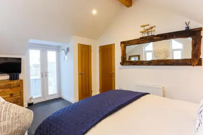 a bedroom with a bed and a mirror at The Lighthouse Penthouse, Studio and Holiday Home in St Ives