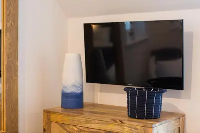 a tv sitting on top of a wooden table with a vase at The Lighthouse Penthouse, Studio and Holiday Home in St Ives