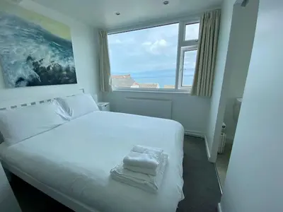 a bedroom with a large white bed with a window at Coast Accommodation in St Ives