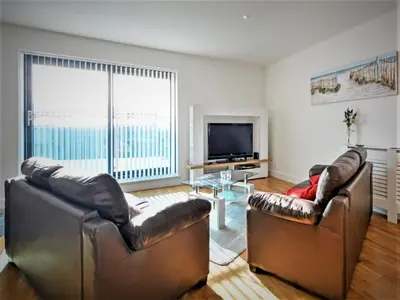a living room with two leather chairs and a television at SeaQuest 8 in Newquay