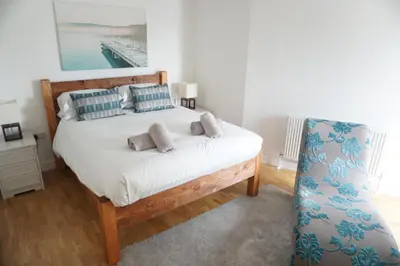 a bedroom with a bed and a chair at SeaQuest 8 in Newquay