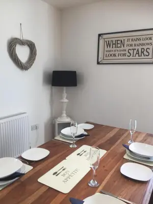 a wooden table with white plates and glasses on it at SeaQuest 8 in Newquay
