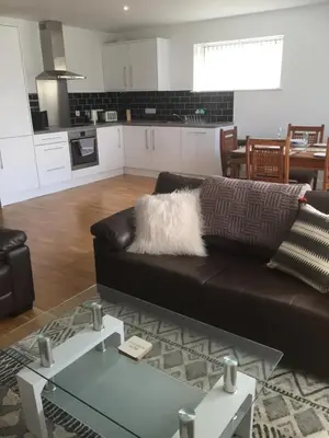 a living room with a brown couch and a kitchen at SeaQuest 8 in Newquay