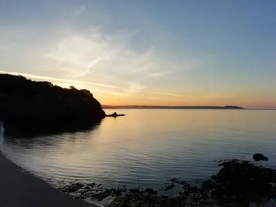 a sunset over a large body of water at Porthpean Apartment in Charlestown