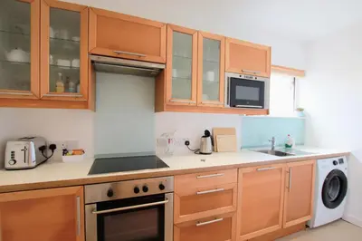 a kitchen with wooden cabinets and a stove top oven at Porthpean Apartment in Charlestown