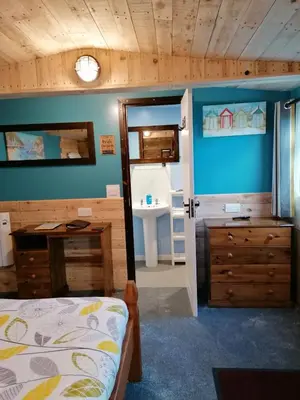a bedroom with a bed and a sink and a mirror at Pensalda Guest House in Newquay