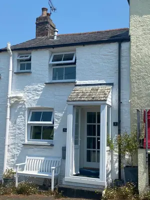 a white house with a bench in front of it at Froglets in Tregoney