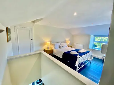 a white room with a bed and a window at Froglets in Tregoney