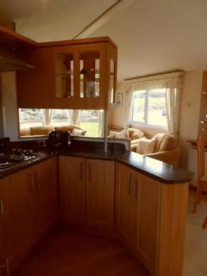 a kitchen with wooden cabinets and a living room at Peace and quiet in countryside location near Perranporth in Perranzabuloe