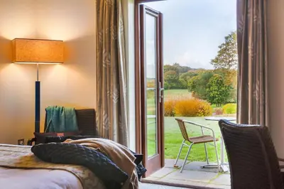 a bedroom with a bed and a sliding glass door at Lanhydrock Hotel & Golf Club in Bodmin