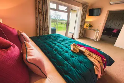 a bedroom with a large green bed with a window at Lanhydrock Hotel & Golf Club in Bodmin