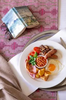 a plate of breakfast food on a table with a book at Lanhydrock Hotel & Golf Club in Bodmin