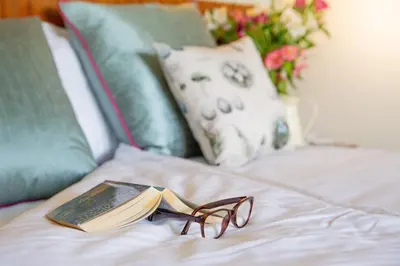 a book and glasses sitting on top of a bed at Lanhydrock Hotel & Golf Club in Bodmin