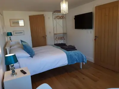 a bedroom with a white bed with blue pillows and a television at Primrose House in St Ives