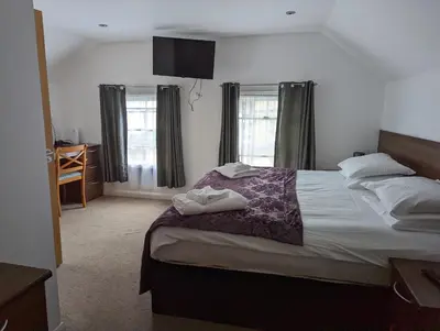 a bedroom with a large bed and two windows at Barley Sheaf, Old Bridge Street EN SUITE ROOMS, ROOM ONLY in Truro