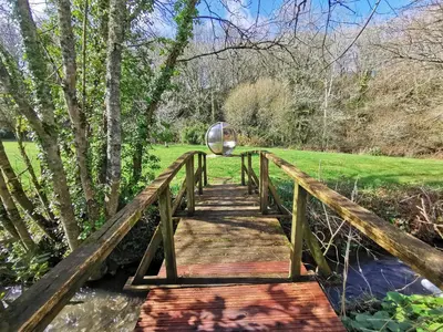 a wooden bridge over a river with a metal object on it at Rose in Vale Country House Hotel in St. Agnes