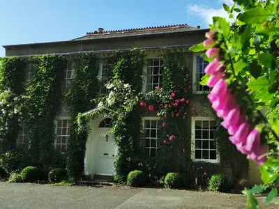 a house with flowers and a white door at Rose in Vale Country House Hotel in St. Agnes