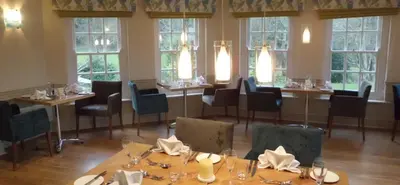a dining room with tables and chairs and windows at Rose in Vale Country House Hotel in St. Agnes