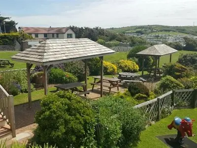 a garden with picnic tables and umbrellas at Widemouth Manor Hotel in Widemouth Bay