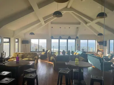 a living room with couches and tables and windows at Widemouth Manor Hotel in Widemouth Bay